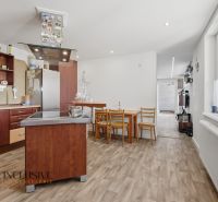 A kitchen in a family house with wooden floor decor, a dining table, and modern appliances.