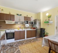 A kitchen in a family house with a wooden decor floor, a dining table, and appliances.