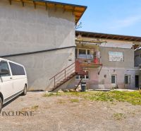 A family house in the village of Dúbravica with a balcony, staircase, and a white van parked next to it.