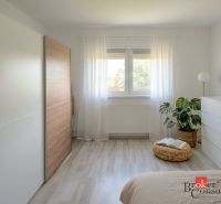 Bright bedroom in a 4-room apartment with minimalist furniture and a wooden decor floor.