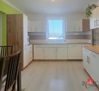 Kitchen in a 4-room apartment with white cabinets and wooden decor on the floor.