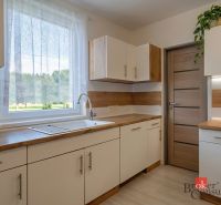 A kitchen in a 4-room apartment with a wooden decor floor and a view of the garden.