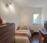 Bedroom in a 4-room apartment with wood-patterned flooring and simple furnishings.