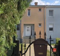 Entrance to a terraced house with a gate, trees, and a mailbox in Blatná na Ostrove.