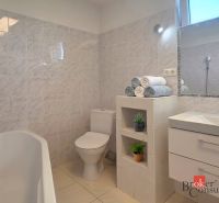 Bathroom in a 4-room apartment with a bathtub, sink, and toilet, light tiles.