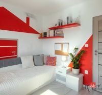 A children's room in a 4-room apartment with red decorations and simple furniture.