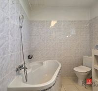 A bathroom in a 4-room apartment with a bathtub, toilet, and a shelf with towels.