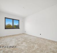 A room in a family house with a concrete floor and a large window.