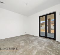The interior of a family house with a concrete floor and large windows to the terrace.