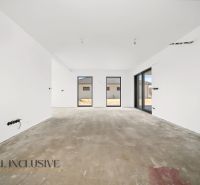 A spacious room in a family house with a concrete floor and large windows.