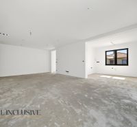 A spacious room in a family house with a concrete floor and a large window.