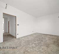 An unfurnished room with white walls and a raw floor in a family house.