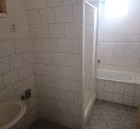 A bathroom with a bathtub, shower, and sink tiled in a family house.
