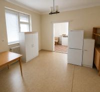 A room with a wooden table, a wardrobe, and a refrigerator in a family house.
