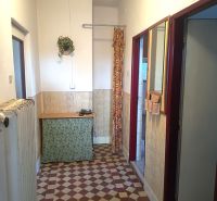 A hallway with retro tiles, a small table, and a curtain in a family house.