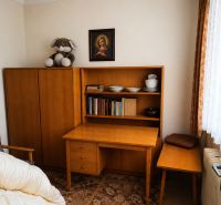 A room in a family house with wooden furniture, books, and decorative items.