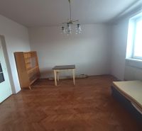 A bright room with a wooden decor floor, a table, and a dresser in a family house.
