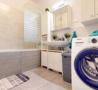 Spacious bathroom in a 3-room apartment with a bathtub and a washing machine, light tiles.
