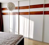 A bedroom in a three-room apartment with a wooden decor floor and a built-in wardrobe.