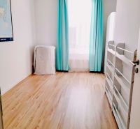 A room in a 3-room apartment with a wood-patterned floor and turquoise curtains.