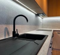 A kitchen unit with a black sink and modern lighting in a studio apartment.