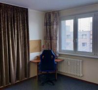 A desk by the window in a studio apartment with curtains and a view.