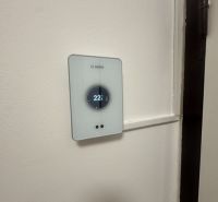 Thermostat on the wall in a 2-room apartment, temperature set to 22°C.
