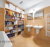 A bathroom in a 3-room apartment with books, two sinks, and tiles.