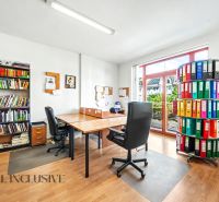 An office with a large window, two chairs, shelves with books, and a floor with a wooden decor.