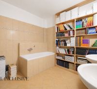 A bathroom with a bathtub and shelves full of books in a 3-room apartment.