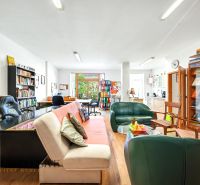 Living room in a three-room apartment with a wooden decor floor, a bookshelf, and a sofa.