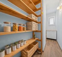 Pantry with shelves and groceries in a family house, floor with wooden decor.