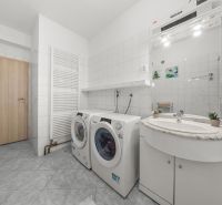 Washing machine and dryer in the bathroom of a family house with white tiles and a mirror.