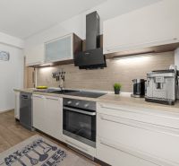 A kitchen in a family house with a wooden decor floor, equipped with a coffee machine and a stove.