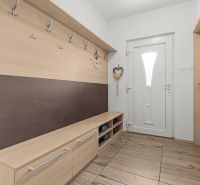 Entrance hallway of a family house with a coat rack wall and white doors.