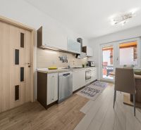 A kitchen in a family house with a kitchen unit, a dining table, and balcony doors.
