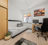A room in a family house with a wooden decor floor, a table, and a comfortable armchair.