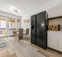A kitchen in a family house with a refrigerator, a dining table, and a floor with a wooden decor.