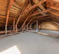 Attic in a family house with wooden beams and a concrete floor.