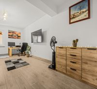 Living room with wood-patterned flooring, a desk, and a television in a family house.