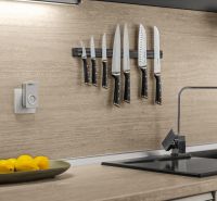 A kitchen in a family house with knives on the wall, a bowl of lemons, and a faucet.