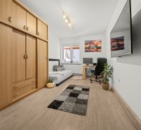 A room in a family house with a desk and a large wardrobe, wooden decor flooring.
