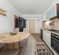 A kitchen in a family house with a dining table and a wooden-patterned floor.