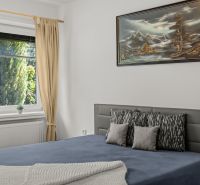A bedroom in a family house with a painting, a bed, and a view of the garden.
