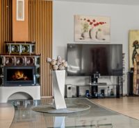 A family house with a tiled stove and a decorative vase on a glass table.