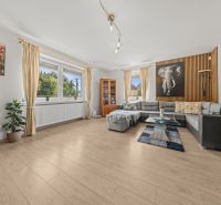 Living room in a family house with a wooden decor floor, a corner sofa, and decorations.