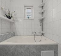 A bathroom with a bathtub and white tiles in a family house.