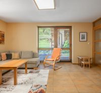 Living room in a family house with a corner sofa, an armchair, and access to the terrace.
