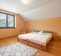 Bedroom with wood-patterned flooring in a family house, light furniture, and a window with a view.