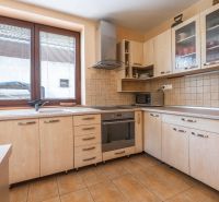 A kitchen in a family house with wooden decor and appliances, light-colored countertop.